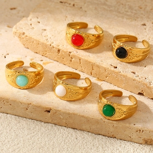 Set of five vintage gold rings with colorful stones on natural beige stone background