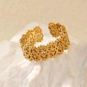 Detail shot of a hollow lace pattern gold-plated stainless steel open ring on a stone