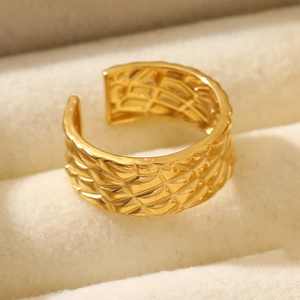 Detail of a golden wide open ring with geometric quilted pattern in a soft jewelry box