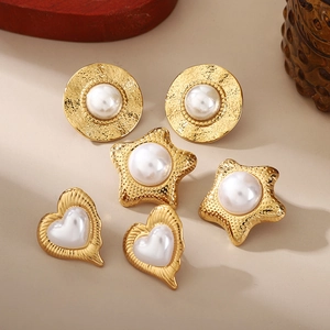 Golden flower earrings set with white pearls and hammered metal texture in warm studio lighting