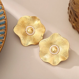 Detail of golden flower earring with brushed metal petals and pearl center detail