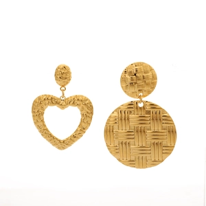 Detail of asymmetric gold earrings with hammered heart and woven circular patterns