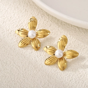 Close-up of golden flower earrings with white pearl center on an elegant background