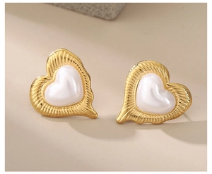 Macro detail of gold plated heart earrings with pearl inlay and wavy metal texture
