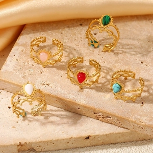 Set of five vintage open rings with colorful stones on a textured stone surface