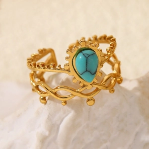 Macro shot of 18k gold open ring with teardrop turquoise on white coral stone