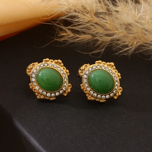Détail de boucles d'oreilles vintage avec pierre verte, cristaux et relief en or poli