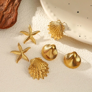 Detailed view of gold starfish and seashell stud earrings on a minimalist artistic display