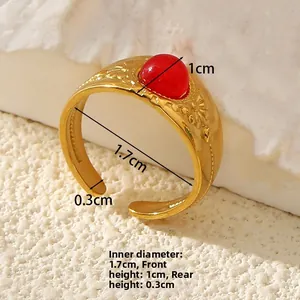 Close-up of gold stainless steel ring with red stone and embossed floral texture