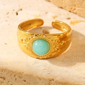 Vintage bohemian open ring in gold finish with a round turquoise stone on stone surface