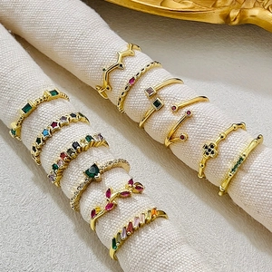 Detailed view of colorful zircon heart and star gold rings on fabric texture