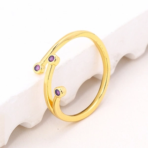 Macro detail of gold-plated open ring with purple zircon stones on a marble surface