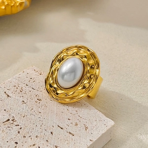 Macro shot of an oversized geometric gold ring featuring irregular textures and an oval pearl