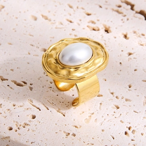 Close-up of irregular textured gold stainless steel ring featuring an oval pearl inlay
