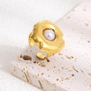 Detail of 18k gold-plated irregular lava ring featuring a white pearl inlay on travertine