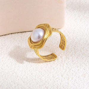 Detail of a gold plated pearl ring featuring triple-ridged wave band on a stone texture