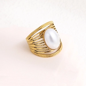 Detail view of gold-tone multi-layer wide ring featuring a large white oval pearl inlay