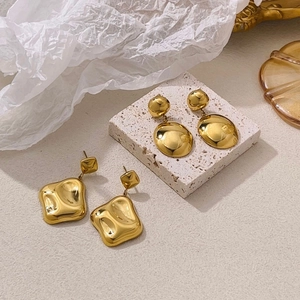 Irregular geometric gold earrings in square and oval designs on a minimalist stone tray
