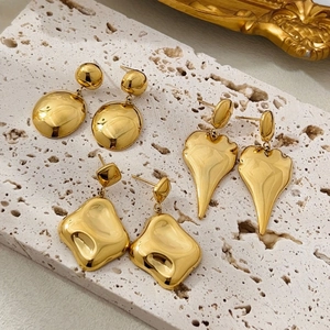 Detailed view of three pairs of textured gold stainless steel geometric earrings on stone
