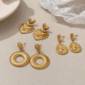 Detailed view of three pairs of vintage gold plated earrings in heart, drop, and hoop shapes