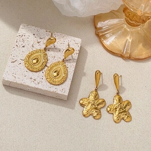 Detail of 18K gold plated earrings with vintage teardrop and star lava textures