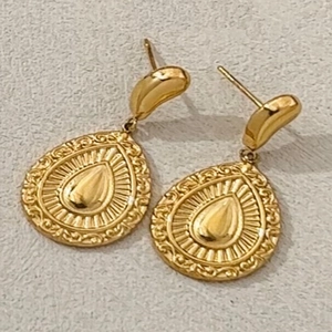 Vintage style gold teardrop earrings with embossed relief on a grey stone base
