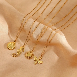 Detail of gold necklaces with scallop, seahorse, sun and bee charms on champagne silk
