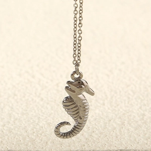 Detailed macro view of the silver seahorse pendant and minimalist steel chain necklace