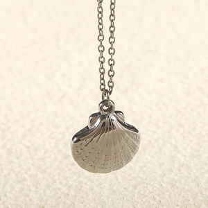 Macro shot of silver scallop shell pendant necklace with polished stainless steel surface
