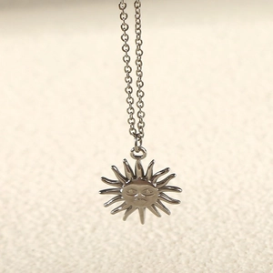 Detailed macro view of silver sunflower pendant necklace with engraved personified face