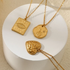 Ensemble de colliers dorés avec pendentifs cœur, abeille et œil sur support en pierre