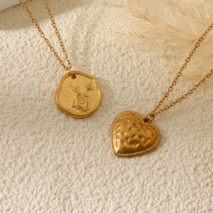 Colliers dorés avec pendentifs pièce abeille et cœur martelé sur fond texturé