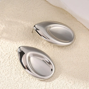 Détail macro de boucles d'oreilles argentées avec surface concave polie et effet miroir