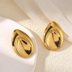 Détail de boucles d'oreilles gouttes dorées brillantes sur un présentoir épuré