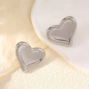 Détail macro de boucles d'oreilles cœur en argent poli sur un plateau en céramique