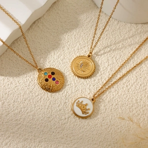 Trois colliers en acier doré avec boussole et pendentifs en pierres colorées