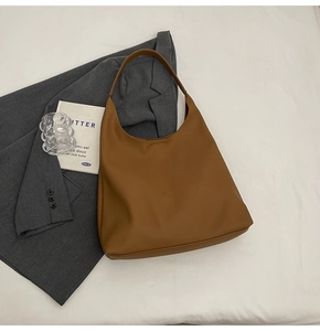 Detail shot of a large brown leather hobo bag placed over a stylish grey blazer coat