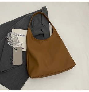 Detail shot of a caramel brown hobo tote bag in leather with chic business props