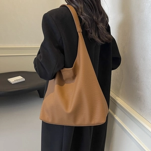 Brown leather large capacity tote bag shown on model with minimalist hobo bag style