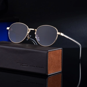 Oval retro sunglasses with gold metal frame and premium leather case on reflective surface
