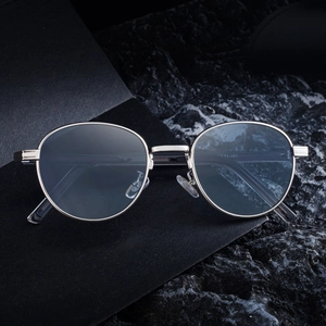 Sleek silver oval sunglasses with blue lenses on a premium textured dark background