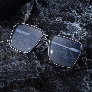 Retro square frame sunglasses for men with black and gunmetal frames on volcanic rock