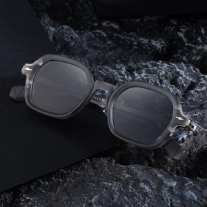 Square translucent grey sunglasses with zinc alloy temples on black stone display