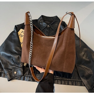 Détail du sac hobo en daim marron avec chaîne argentée et bandoulière en cuir souple