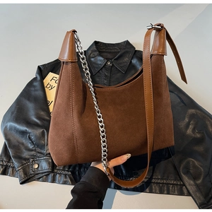 Détail du sac fourre-tout en daim et cuir marron foncé avec chaîne en métal argenté