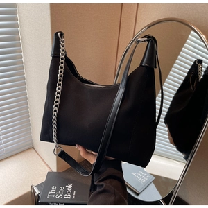 Détail d'un sac cabas noir mat minimaliste avec chaîne argentée et bandoulière en cuir