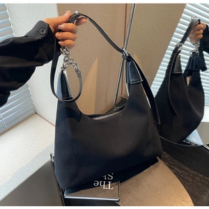 Détail d'un sac porté épaule en daim noir avec chaîne métallique et bandoulière