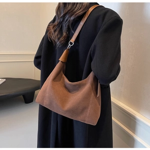 Détail du sac sous l'aisselle en daim marron rétro avec anneau argenté et bandoulière
