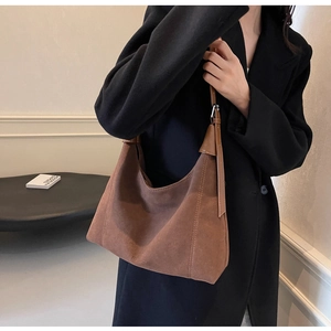 Gros plan d'un sac hobo en daim marron avec bandoulière en cuir et boucle en métal