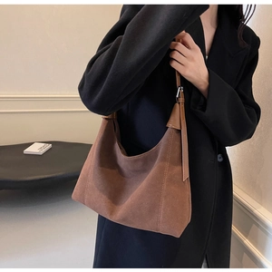 Gros plan du sac hobo en daim marron montrant le logo et la texture du cuir mat